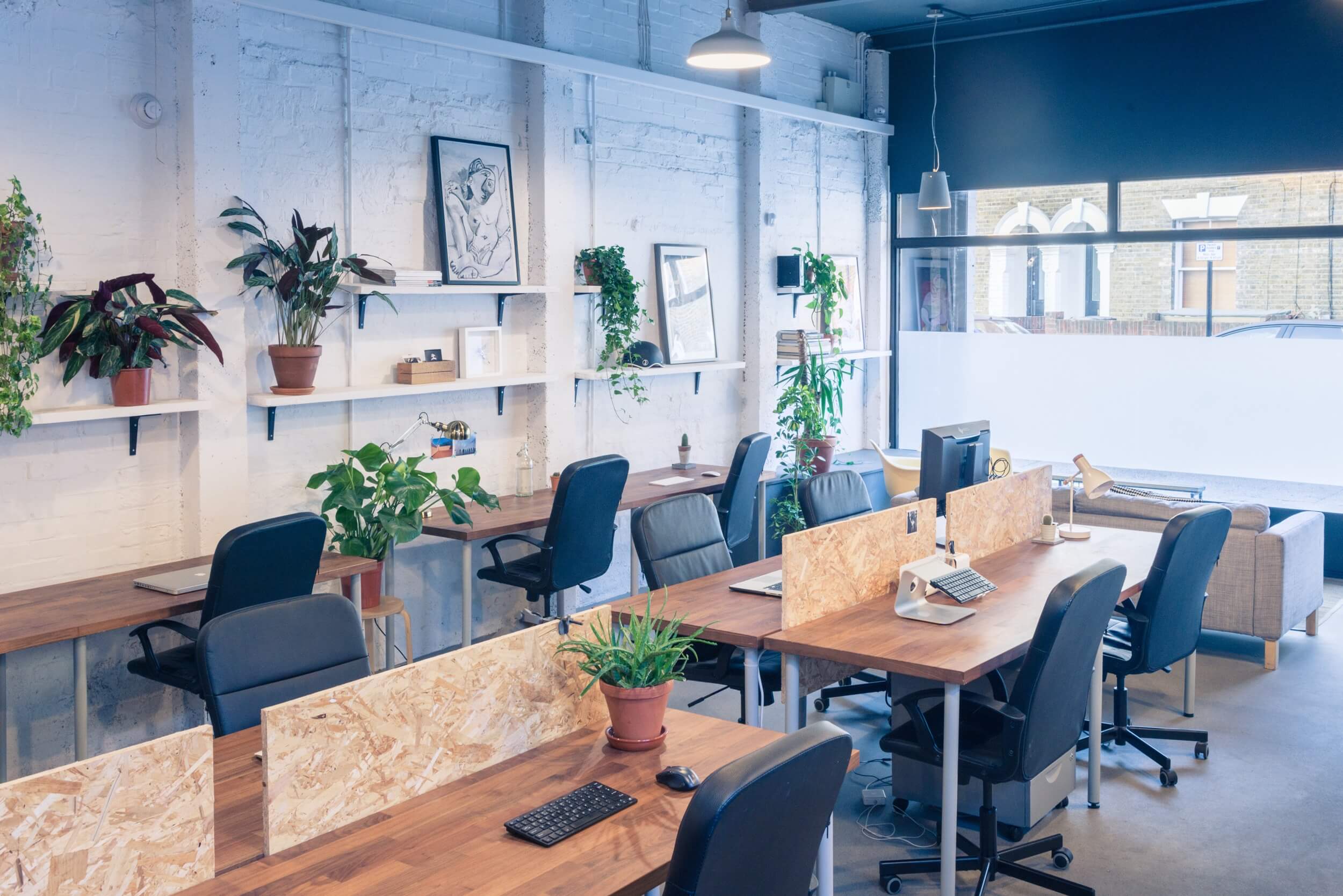 The workroom in daylight, with long timber desks and plants